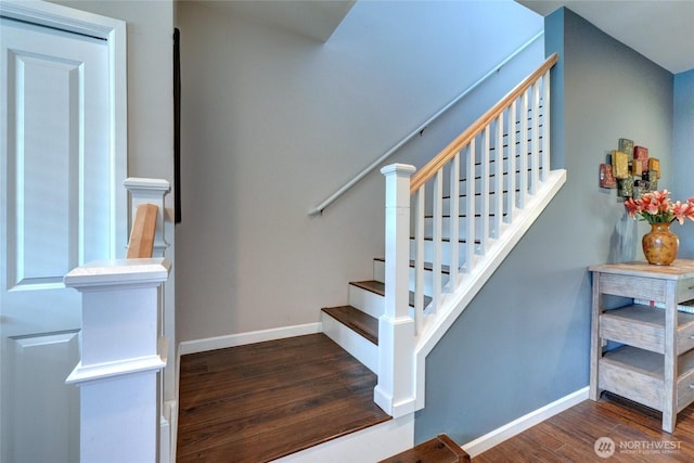 staircase featuring wood finished floors and baseboards