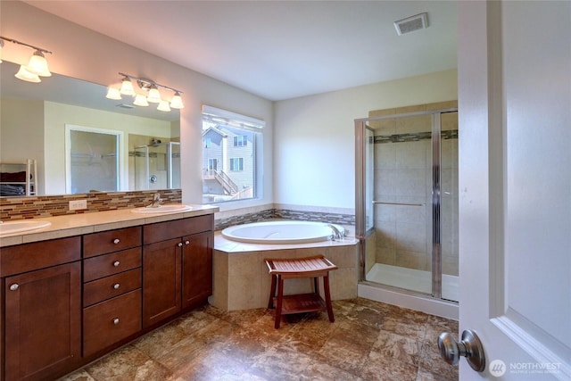 full bathroom with a shower stall, a bath, and double vanity