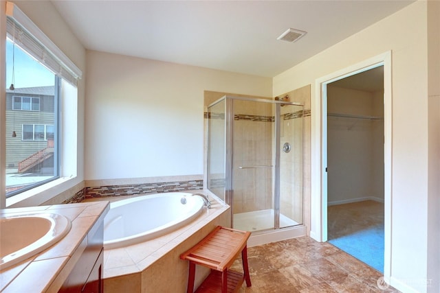 full bathroom with a shower stall, plenty of natural light, a spacious closet, and a bath