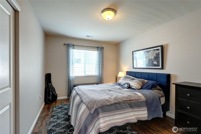 bedroom with dark wood-type flooring and baseboards