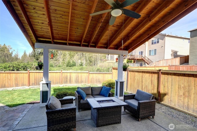 view of patio featuring a fenced backyard, ceiling fan, and an outdoor living space with a fire pit