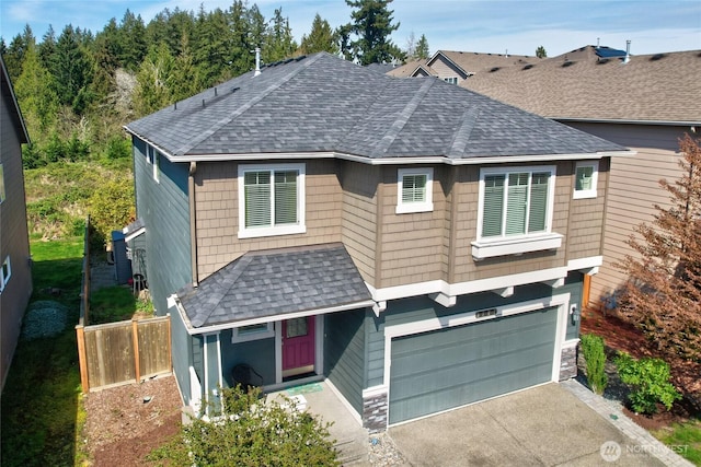 view of front of property featuring roof with shingles, an attached garage, fence, and driveway