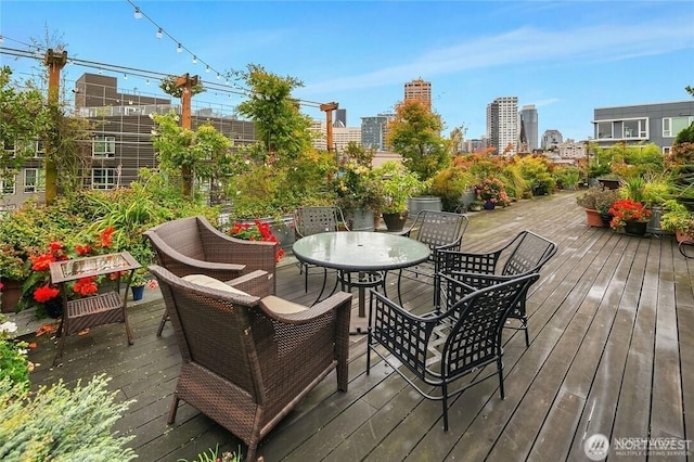 wooden terrace with outdoor dining space and a view of city