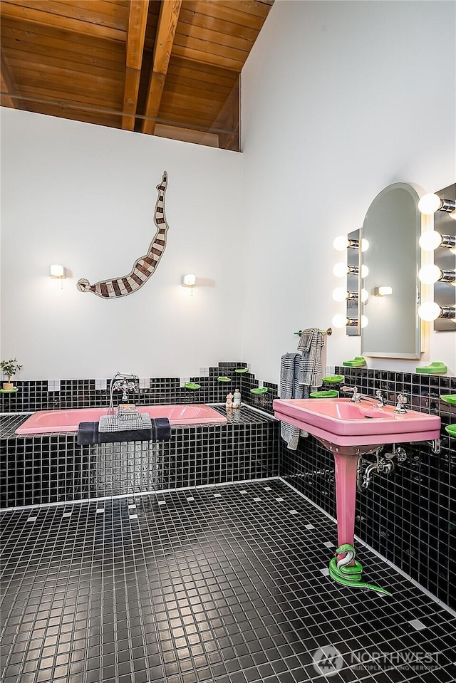interior space featuring tile patterned floors, wooden ceiling, tiled bath, and beam ceiling