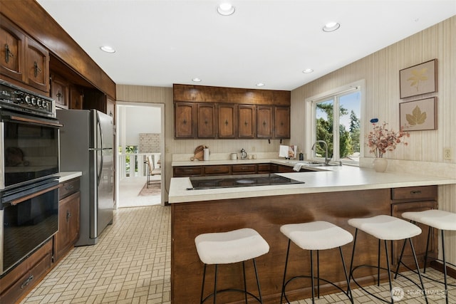 9376 Mercerwood Dr, Mercer Island, WA 98040 - kitchen featuring a sink, black appliances, light countertops, a peninsula, and recessed lighting