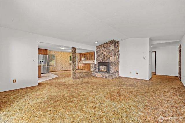 unfurnished living room with a fireplace, carpet, and vaulted ceiling