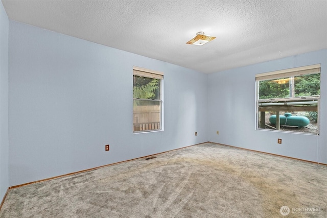 unfurnished room featuring baseboards, a textured ceiling, visible vents, and carpet