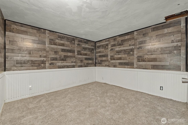 carpeted spare room featuring wooden walls