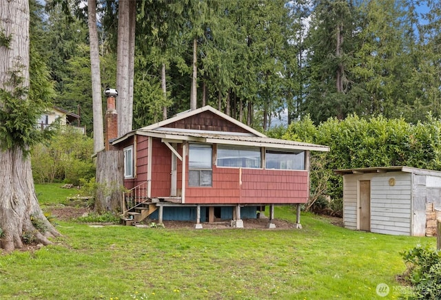 back of property featuring an outdoor structure, a yard, and a storage shed