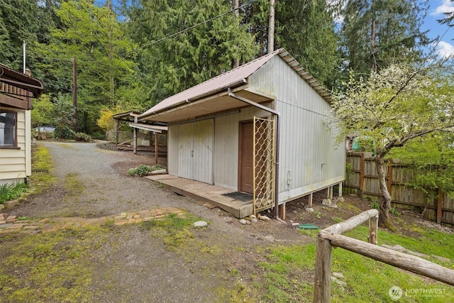 view of outbuilding featuring fence and an outbuilding