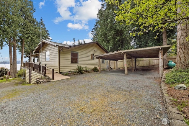 view of front of property with driveway, a carport, and fence