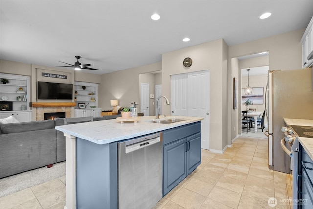 kitchen with appliances with stainless steel finishes, blue cabinets, a sink, ceiling fan, and open floor plan
