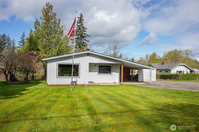 view of front of house with a front yard, an attached carport, and driveway