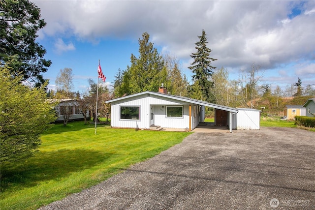 view of front of property featuring an attached carport, driveway, board and batten siding, and a front lawn