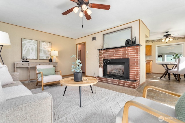 living room with baseboards, a fireplace, a ceiling fan, and visible vents