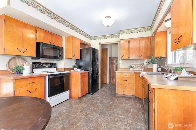 kitchen featuring stone finish flooring, black appliances, light countertops, a sink, and brown cabinets