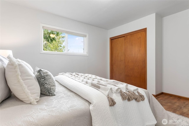 bedroom featuring a closet, baseboards, and wood finished floors