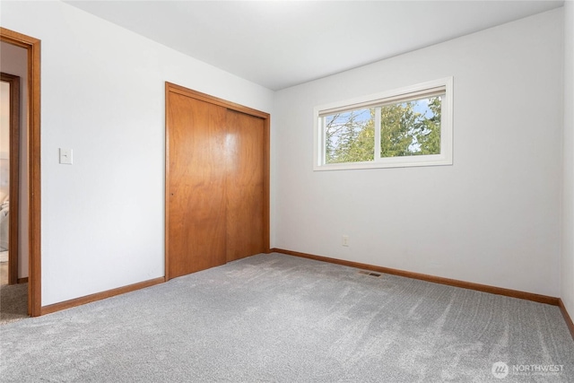 unfurnished bedroom featuring a closet, baseboards, and carpet flooring