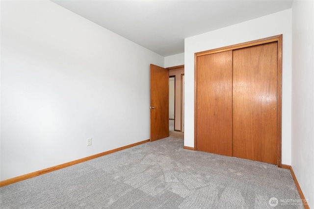 unfurnished bedroom with a closet, baseboards, and carpet floors