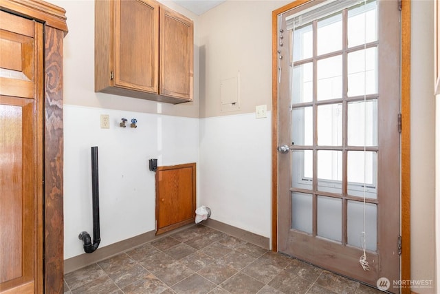 laundry area with a healthy amount of sunlight, baseboards, stone finish flooring, and cabinet space