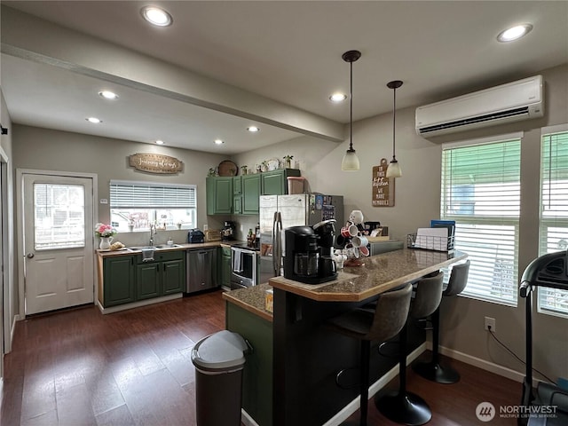 kitchen featuring a wall mounted AC, dark wood-style flooring, a sink, and appliances with stainless steel finishes
