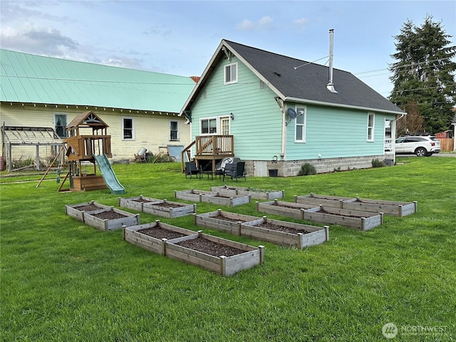 back of property featuring a yard, a vegetable garden, and a playground