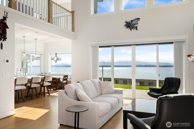 living area featuring wood finished floors, a towering ceiling, plenty of natural light, and a water view