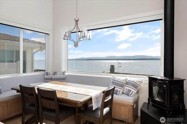 dining room with a wood stove, a notable chandelier, and a water and mountain view