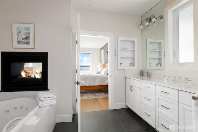 ensuite bathroom featuring ensuite bathroom, built in shelves, a jetted tub, vanity, and tile patterned floors