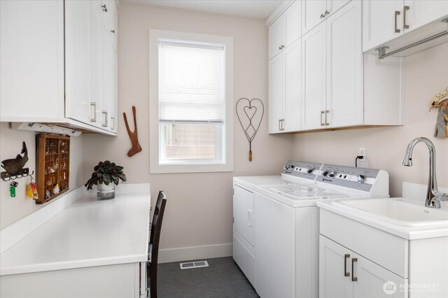 washroom with visible vents, baseboards, a sink, cabinet space, and washing machine and dryer
