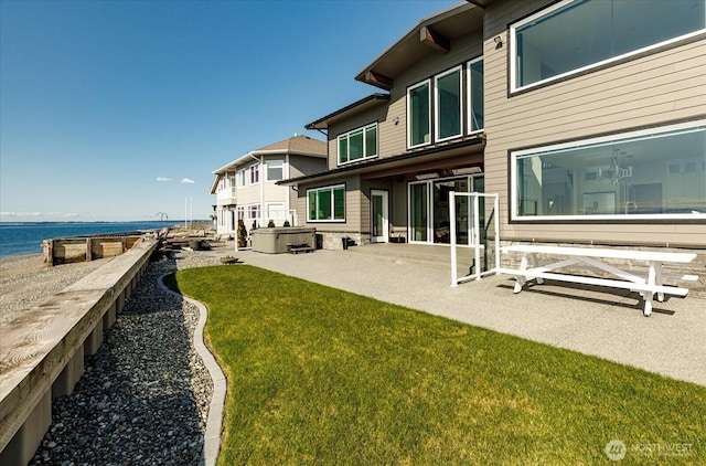 rear view of house featuring a patio area, a yard, and a water view