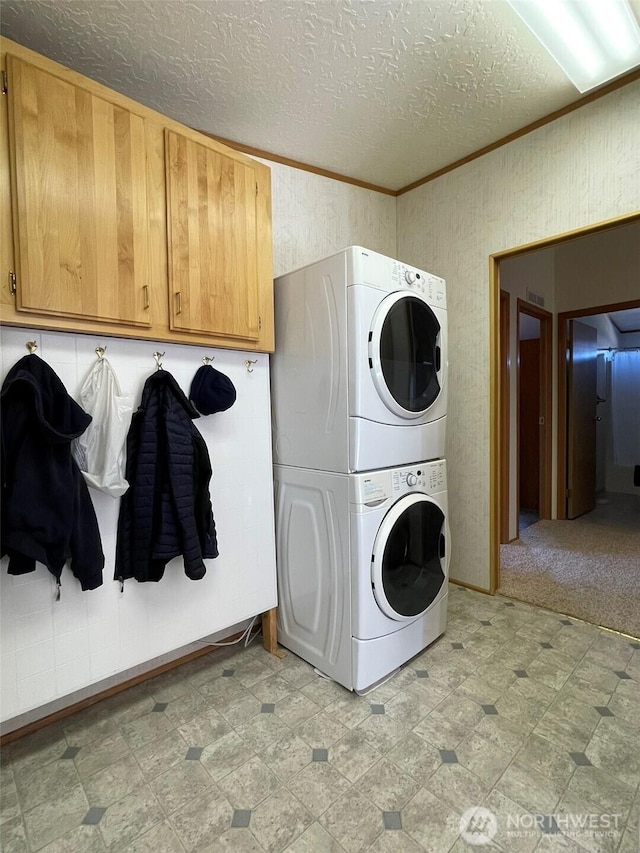 700 Pearl Hill Rd, Bridgeport, WA 98813 - clothes washing area featuring stacked washer / dryer, a textured ceiling, crown molding, cabinet space, and light floors