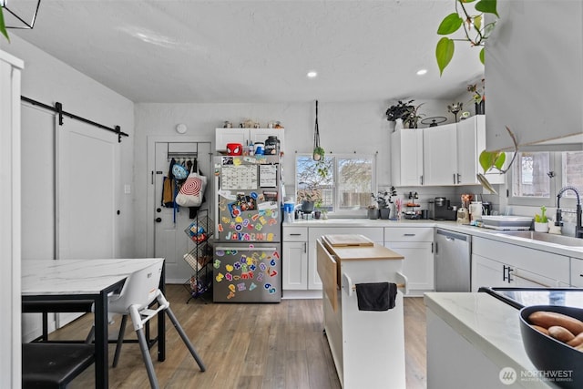 411W 1st Ave, Kennewick, WA 99336 - kitchen with stainless steel appliances, a barn door, white cabinetry, and a sink