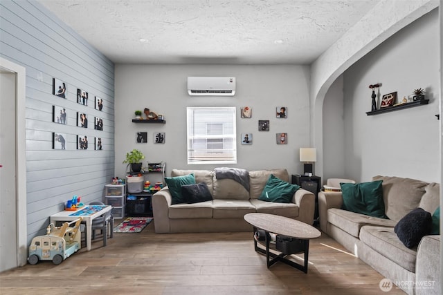 411W 1st Ave, Kennewick, WA 99336 - living room featuring a textured ceiling, arched walkways, wood finished floors, and a wall unit AC