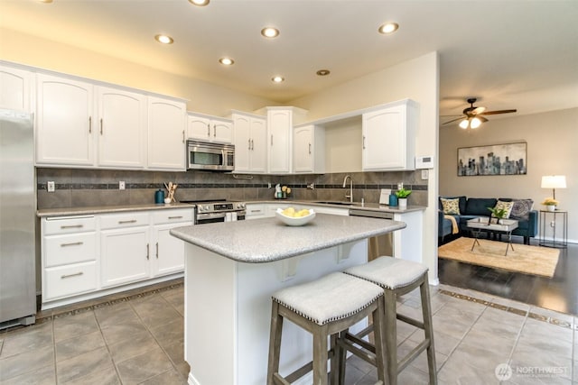 19204 Evergreen Dr, Bonney Lake, WA 98391 - kitchen featuring light tile patterned floors, white cabinetry, a sink, stainless steel appliances, and a breakfast bar area