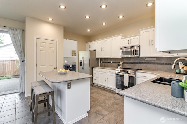 19204 Evergreen Dr, Bonney Lake, WA 98391 - kitchen with a center island, a sink, appliances with stainless steel finishes, white cabinetry, and backsplash