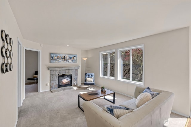 carpeted living room featuring a stone fireplace and baseboards