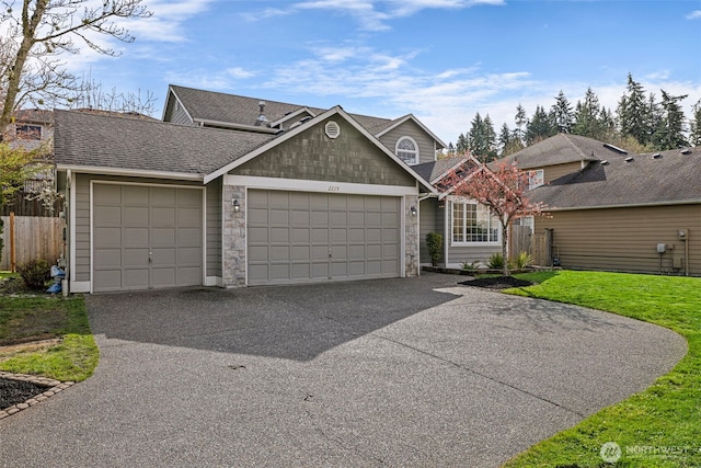 traditional-style house with aphalt driveway, stone siding, a front yard, fence, and a garage