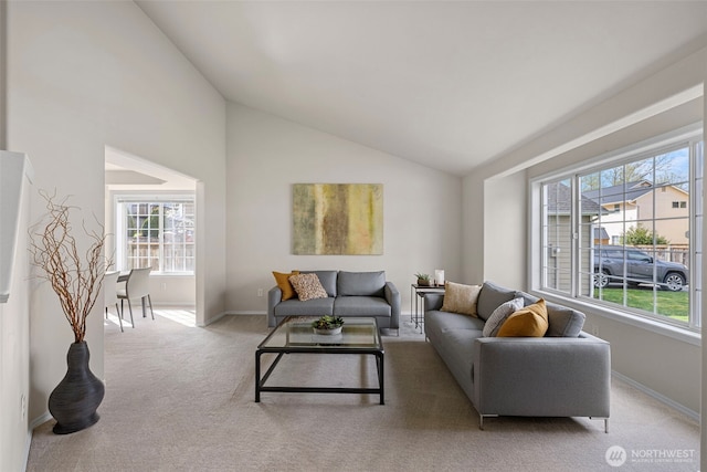 living area with baseboards, high vaulted ceiling, carpet, and plenty of natural light