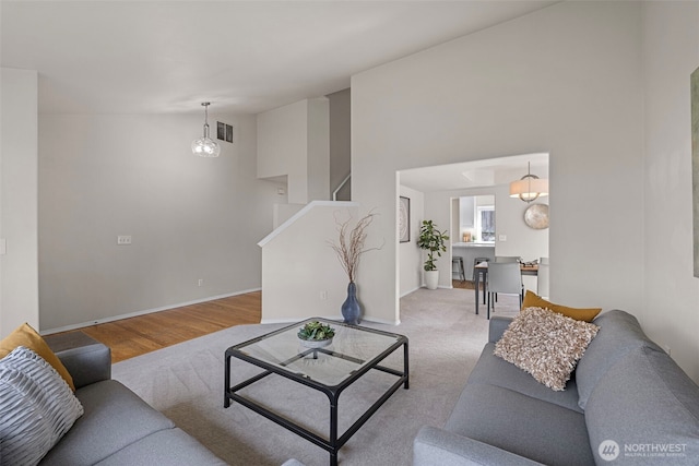 living room featuring visible vents, baseboards, high vaulted ceiling, and stairs
