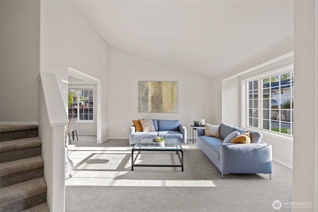 carpeted living room featuring baseboards, high vaulted ceiling, stairway, and a healthy amount of sunlight