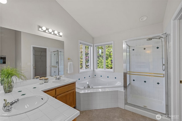 bathroom featuring vaulted ceiling, a stall shower, a garden tub, and a sink