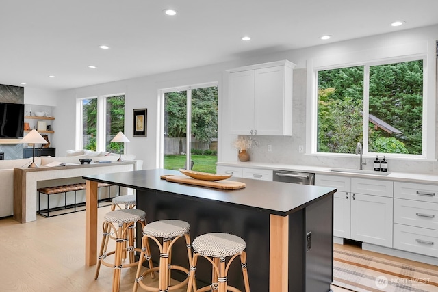 kitchen featuring a kitchen bar, stainless steel dishwasher, a sink, and recessed lighting