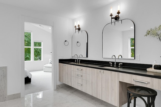 ensuite bathroom with double vanity, ensuite bath, marble finish floor, and a sink