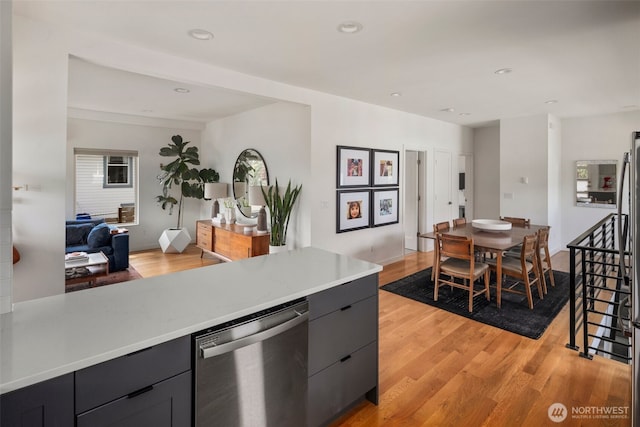 kitchen with stainless steel dishwasher, light wood-style flooring, light countertops, open floor plan, and recessed lighting