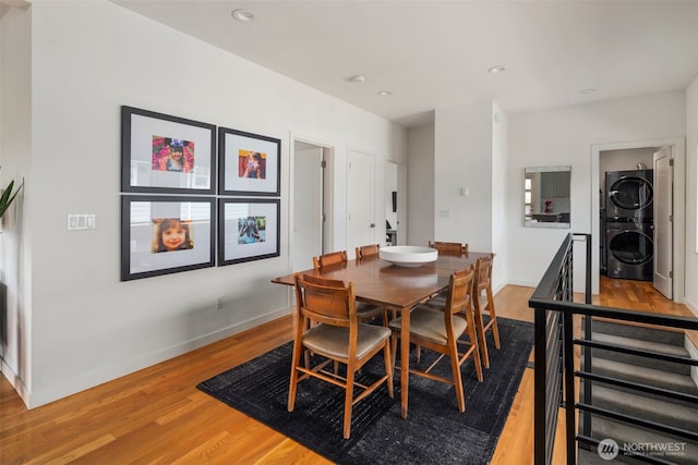 dining room featuring stacked washer and clothes dryer, light wood finished floors, baseboards, and recessed lighting