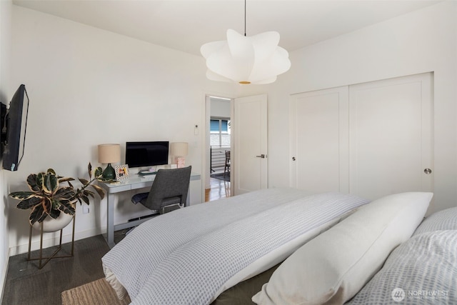 carpeted bedroom featuring a closet, a desk, and baseboards