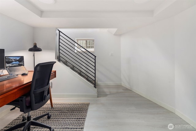 office featuring a tray ceiling, wood finished floors, and baseboards