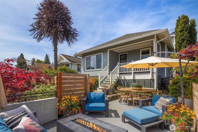rear view of house featuring an outdoor fire pit, a patio area, fence, outdoor dining area, and stairway