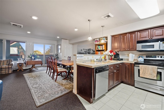 kitchen with a sink, visible vents, a peninsula, and stainless steel appliances